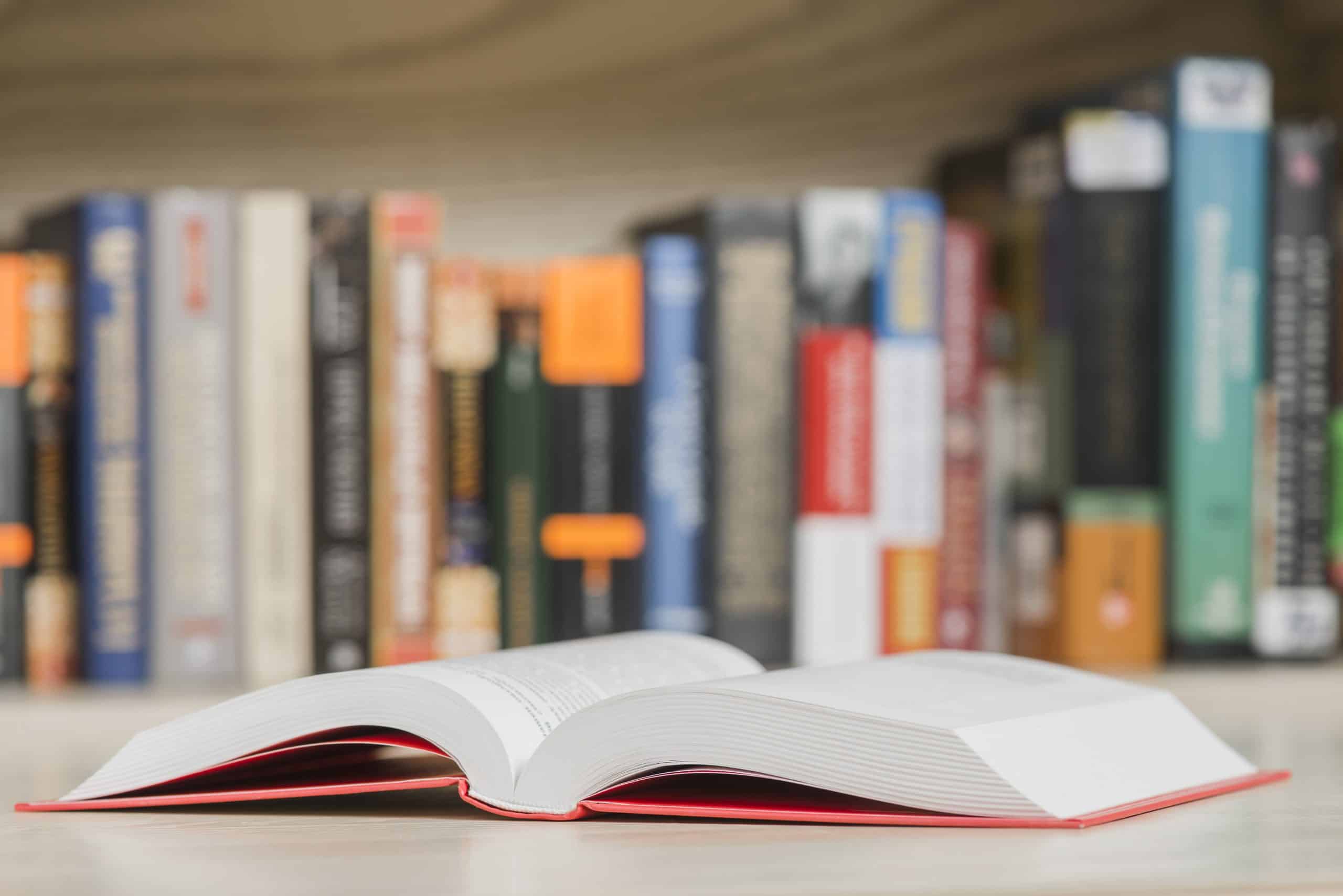 livro aberto sobre uma mesa com outros livros ao fundo