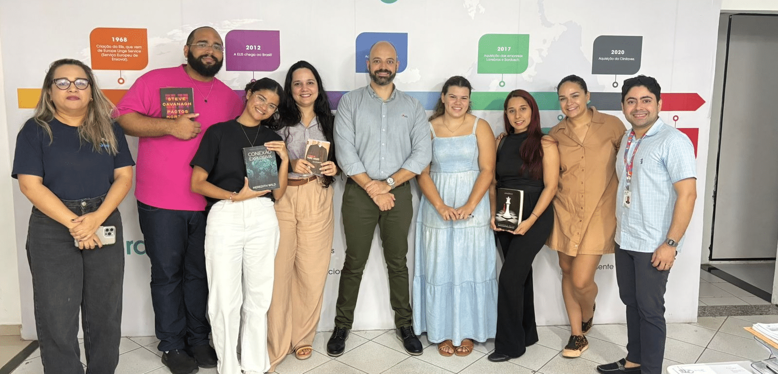 Participantes do evento no RMR de Fortaleza posando para a foto e segurando alguns dos livros doados